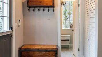 A hallway with a bench, a coat rack, and a door leading to another room.