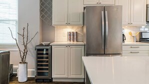 A modern kitchen with white cabinetry, a stainless steel refrigerator, and a built-in oven. - Private Historic Coach House Wicker Park (Chicago)