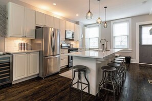A modern kitchen with stainless steel appliances, a central island with bar stools, and pendant lighting.