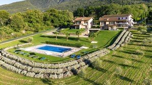 Ein großes Haus mit Swimmingpool, umgeben von einer Steinmauer, eingebettet in eine üppige grüne Landschaft mit Bergen im Hintergrund.