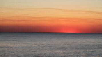 Ein Sonnenuntergang über einem ruhigen Meer mit klarem Horizont.