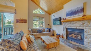 A cozy living room with a stone fireplace, a sofa, and a wooden coffee table. - Central Townhome < 1 Mi to The Village at Mammoth! (Mammoth Lakes)