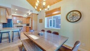 A spacious kitchen with wooden cabinets, a large island, and a dining area with a long table and chairs. - Central Townhome < 1 Mi to The Village at Mammoth! (Mammoth Lakes)