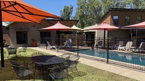 A pool area with lounge chairs and tables, surrounded by a fence, and shaded by large umbrellas. - Adelphi 3 - River views located in the centre of Echuca (Echuca)