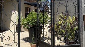 A wrought iron gate with the name "Adelphi" engraved above it, leading to a building with a metal roof and potted plants. - Adelphi 3 - River views located in the centre of Echuca (Echuca)
