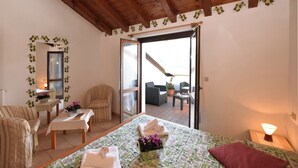 A bedroom with a bed, a chair, a table, and a balcony with outdoor furniture. - Belvedere A (Colico)