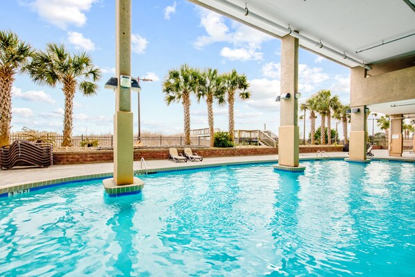A swimming pool with lounge chairs and palm trees.