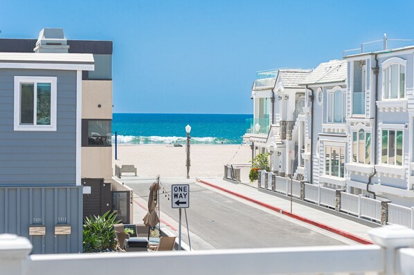 A coastal street with a view of the ocean, a one-way street sign, and buildings with balconies.