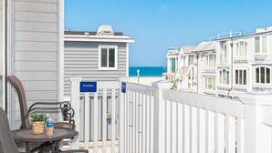 A balcony with a view of the ocean, a 'NO SMOKING' sign, and a table with a chair and a potted plant. - A Guest Favorite! | Fabulously Situated | 1 House from the Beach! | Comfy & Hyper Clean (Newport Beach)