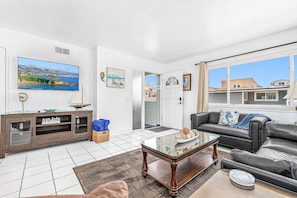 A living room with a TV, a sofa, a coffee table, and a view of the outside.