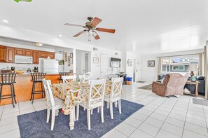A spacious kitchen with white cabinets, a dining area with a table and chairs, and a ceiling fan.