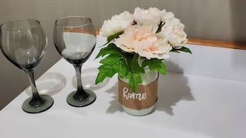 Two wine glasses and a vase with flowers on a white table.