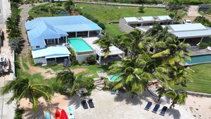 A resort with a swimming pool, multiple buildings, and a beach area with kayaks and paddleboards.