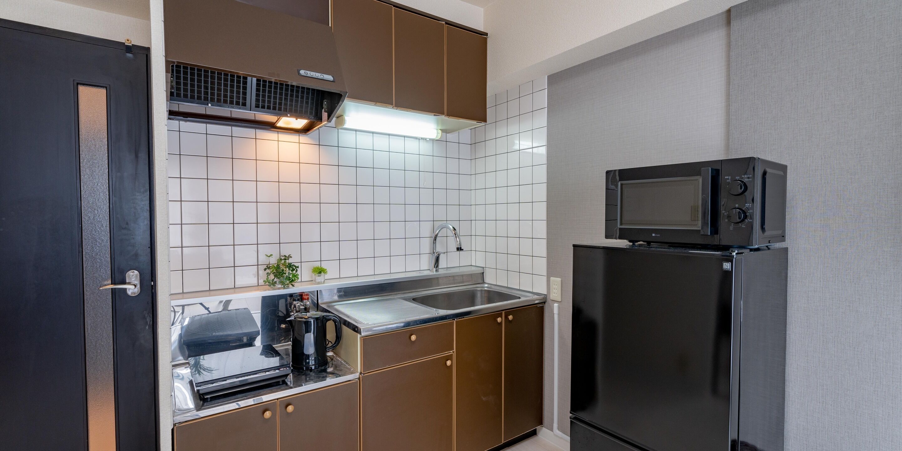Cocina compacta con microondas, lavamanos y electrodomésticos de acero inoxidable.