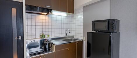 Cocina compacta con microondas, lavamanos y electrodomésticos de acero inoxidable.
