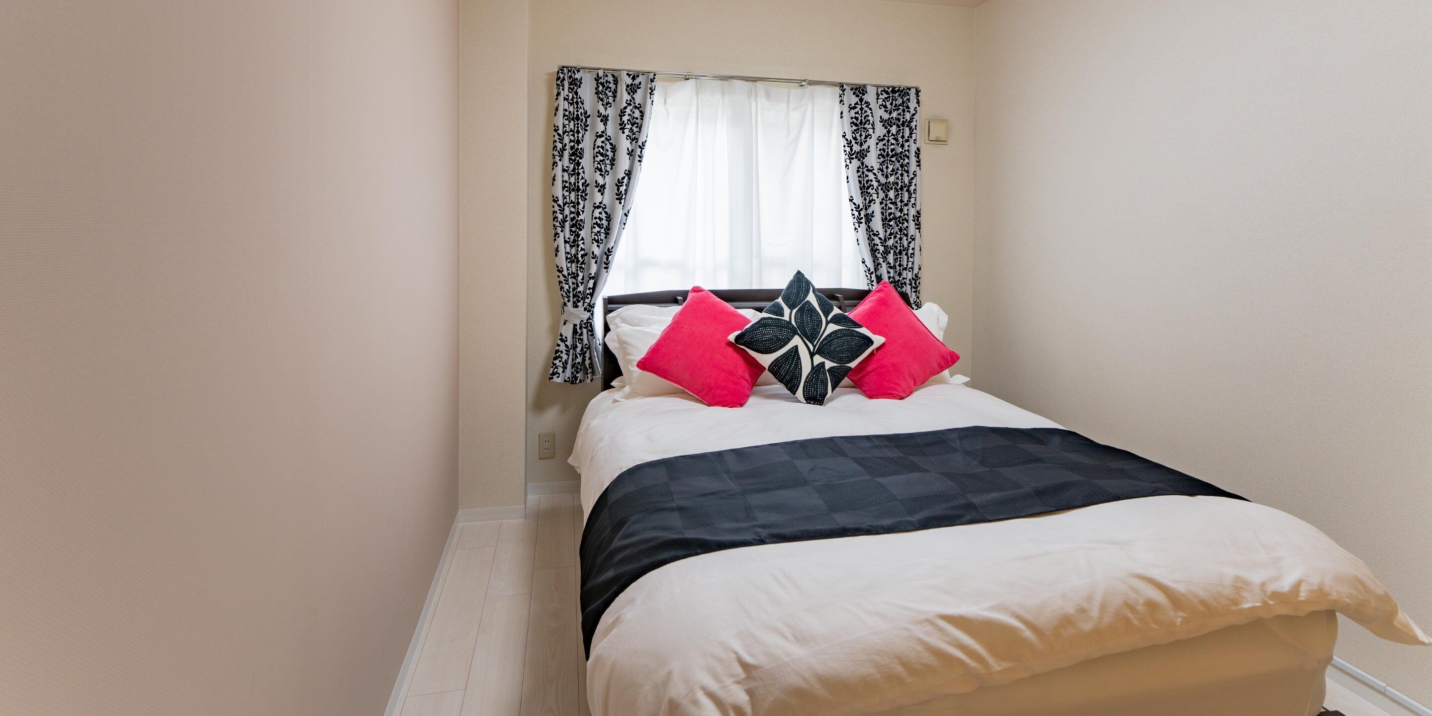 A neatly made bed with a black and white checkered bedspread, two pillows with a black and white pattern, and a white pillow.