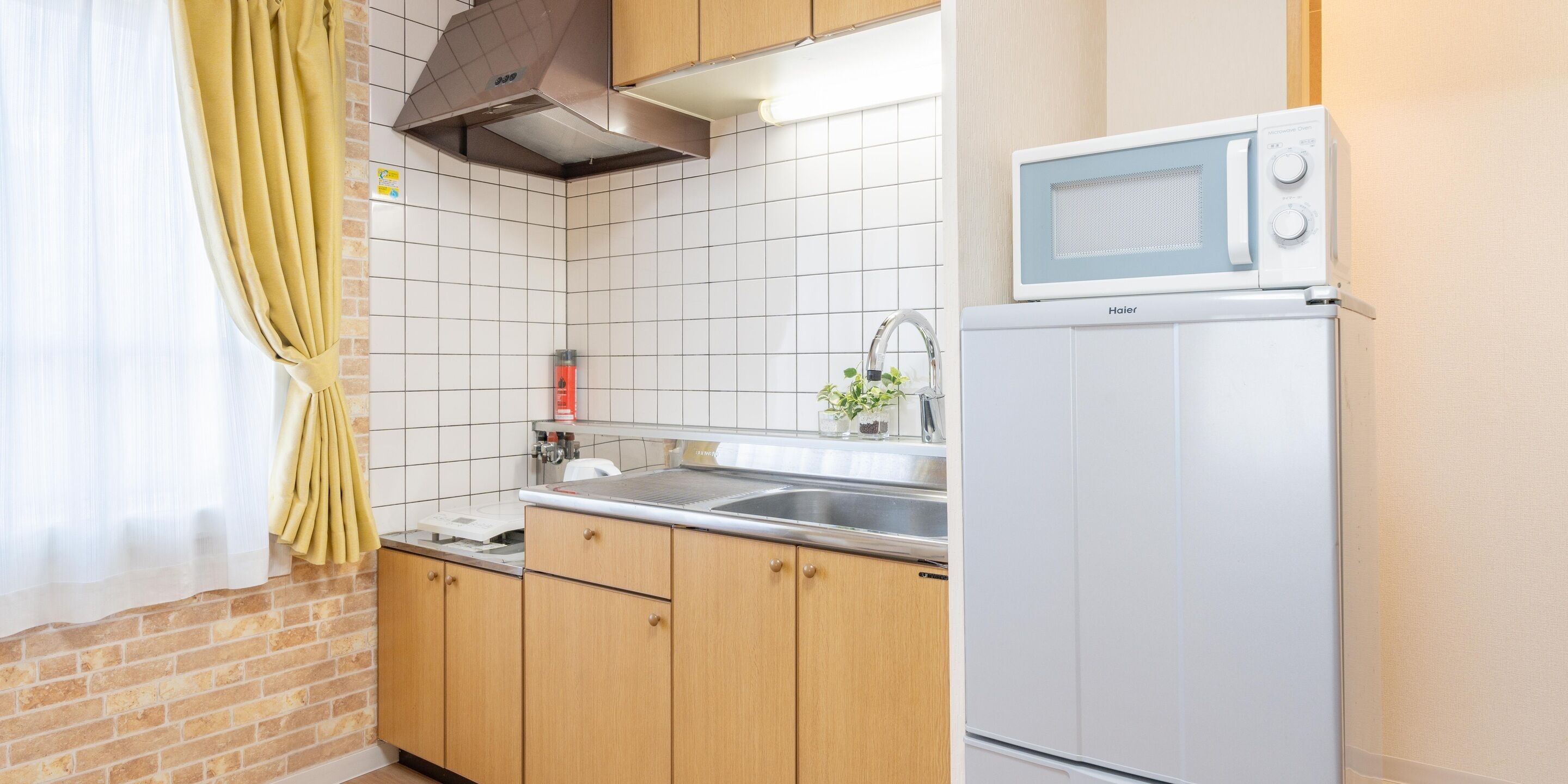 Une cuisine équipée d’un four à micro-ondes, d’un évier et de meubles de rangement en bois.