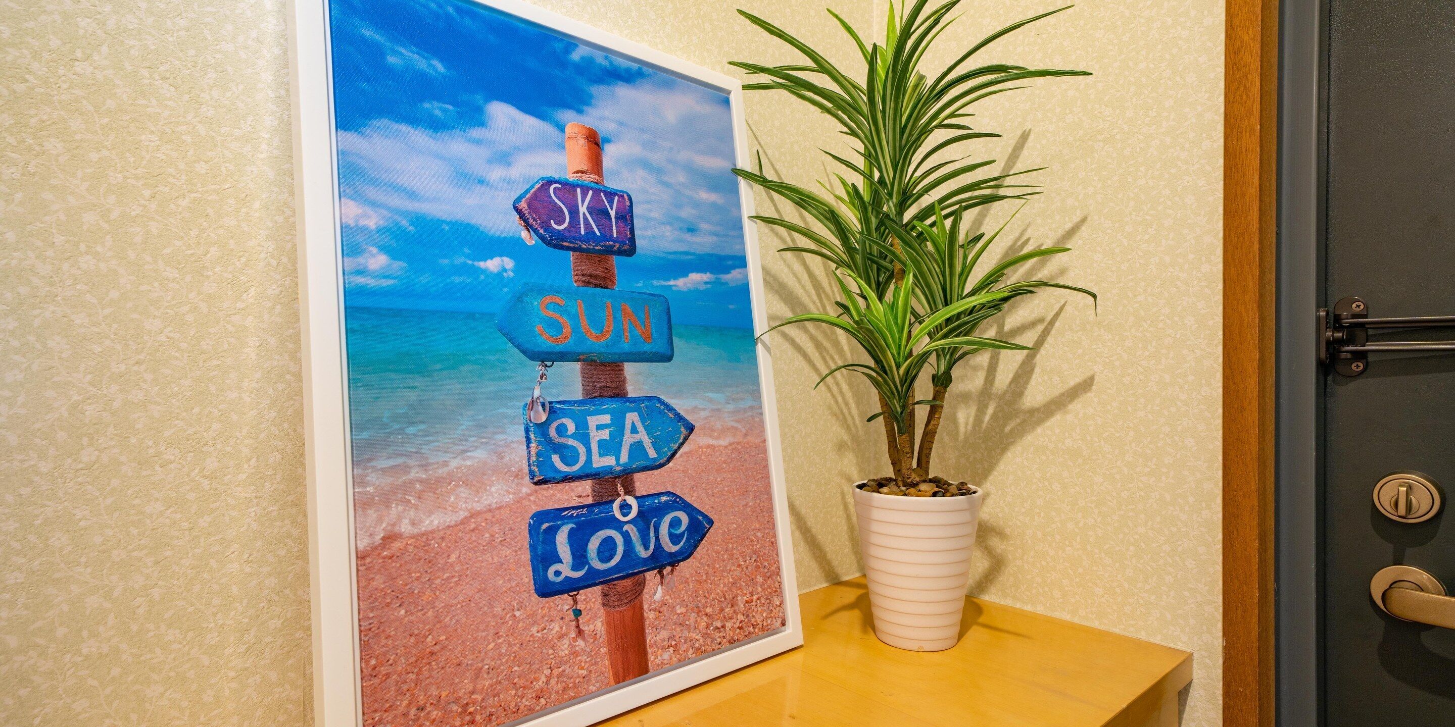 Un muro con un quadro che raffigura una spiaggia e un segnale stradale con indicazioni.