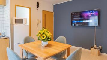 Una cocina moderna con armarios blancos, un microondas y una mesa de comedor de madera con dos sillas. Un jarrón con girasoles está sobre la mesa.