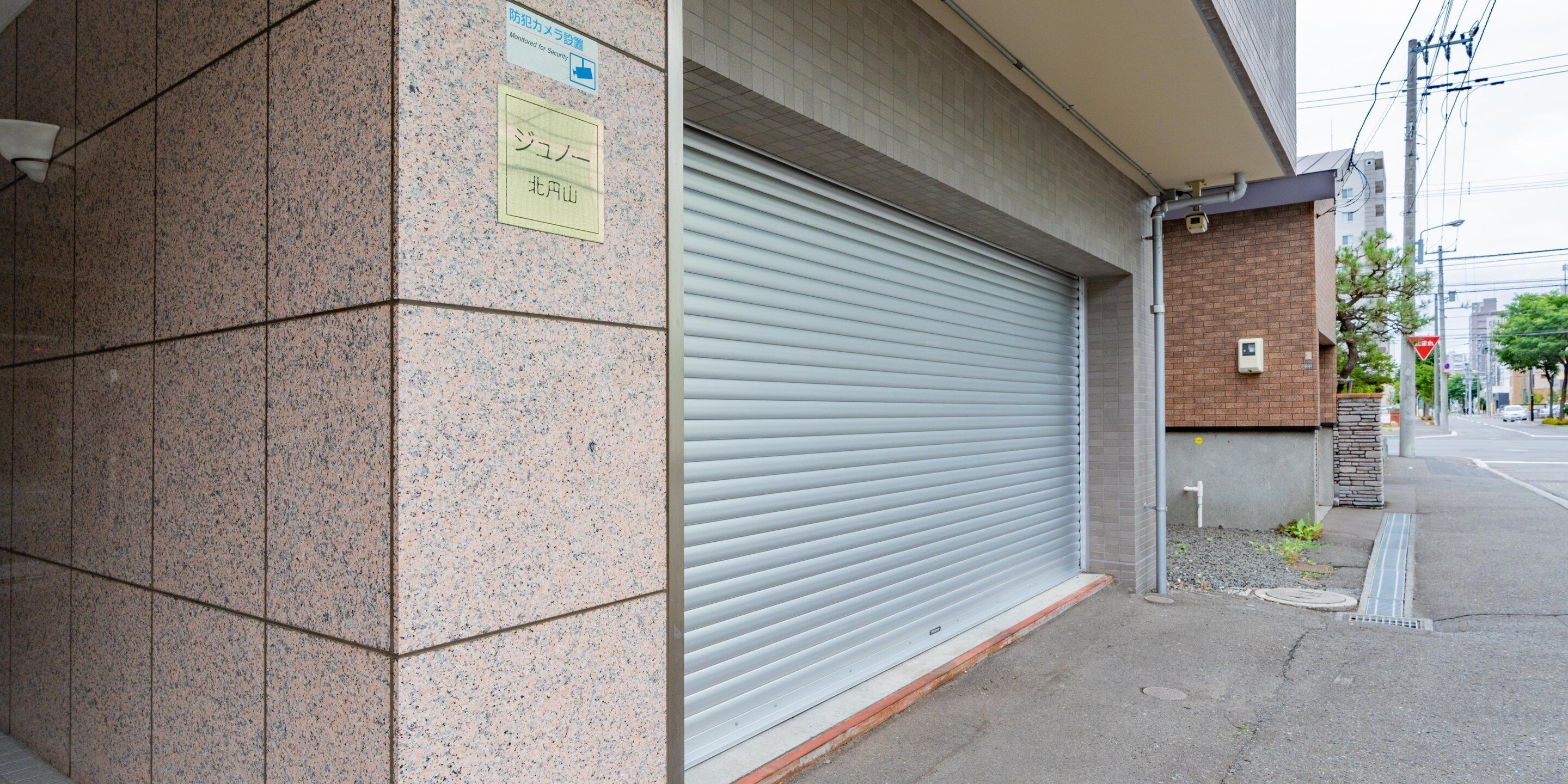 Ein Gebäude mit geschlossenem Rollo, einem Schild, das einen überwachten Bereich kennzeichnet, und einer Kachelwand.