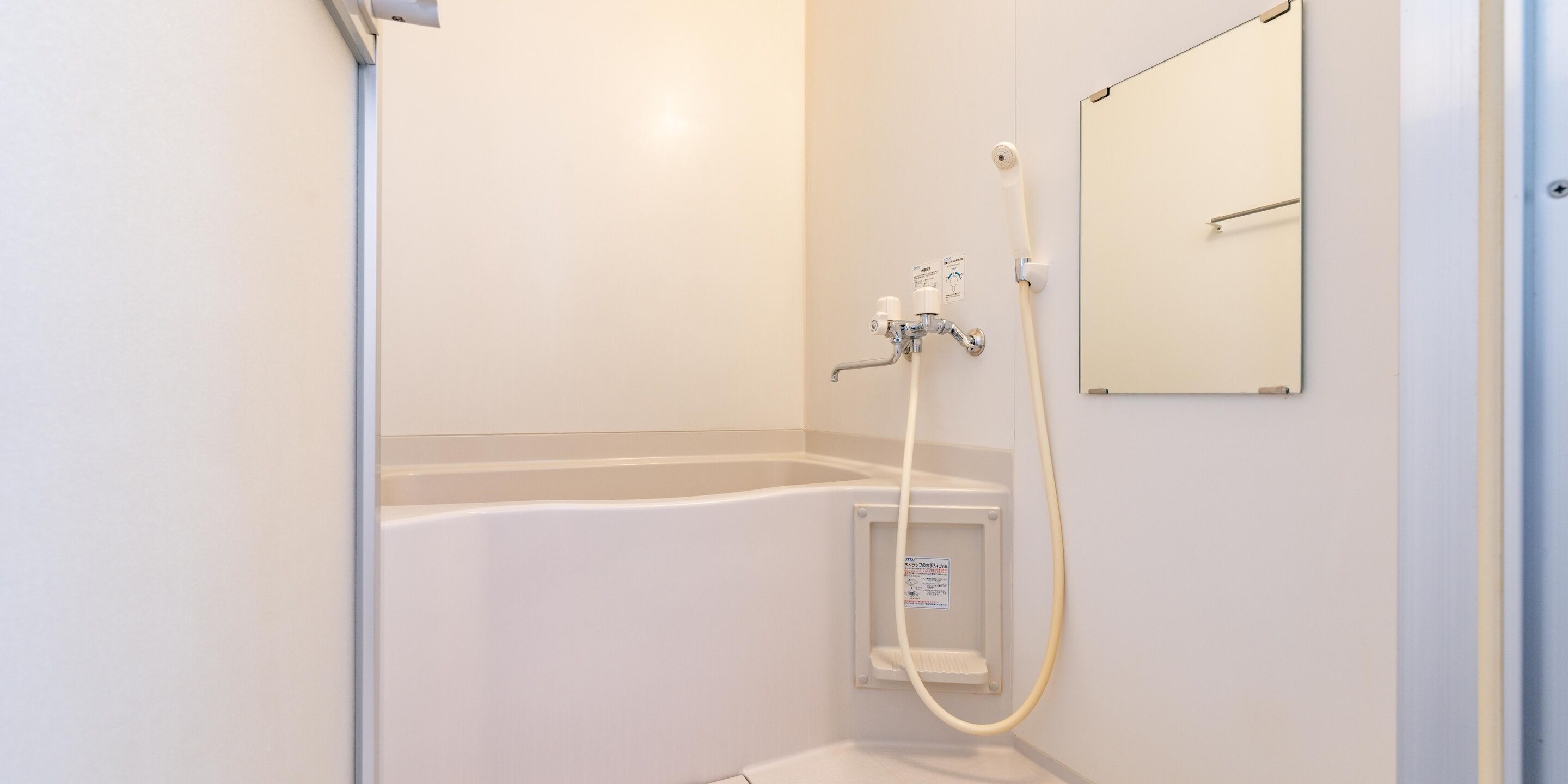 A bathroom with a shower, a toilet, and a mirror on the wall.