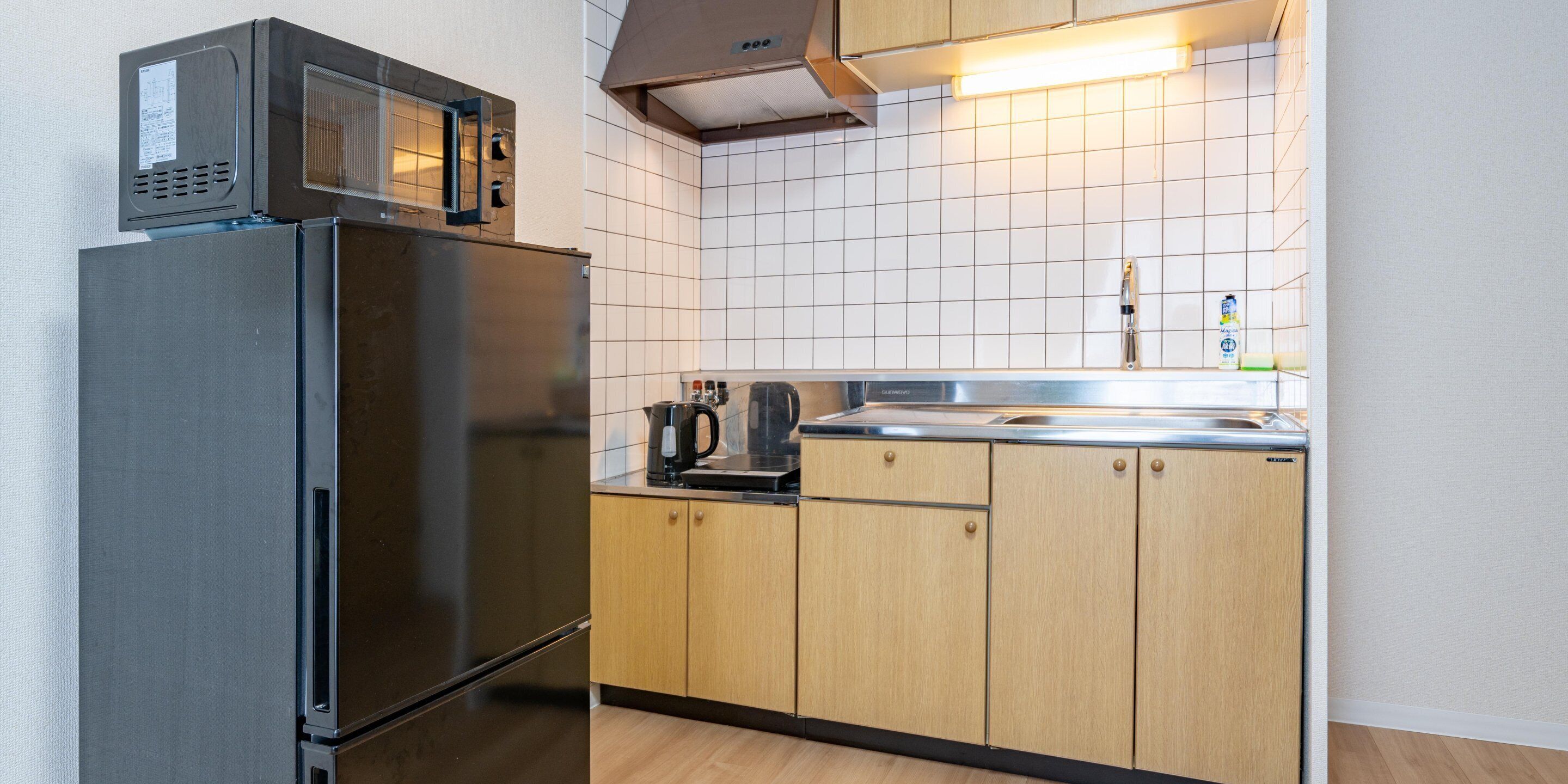 A compact kitchen with a refrigerator, microwave, and wooden cabinets.