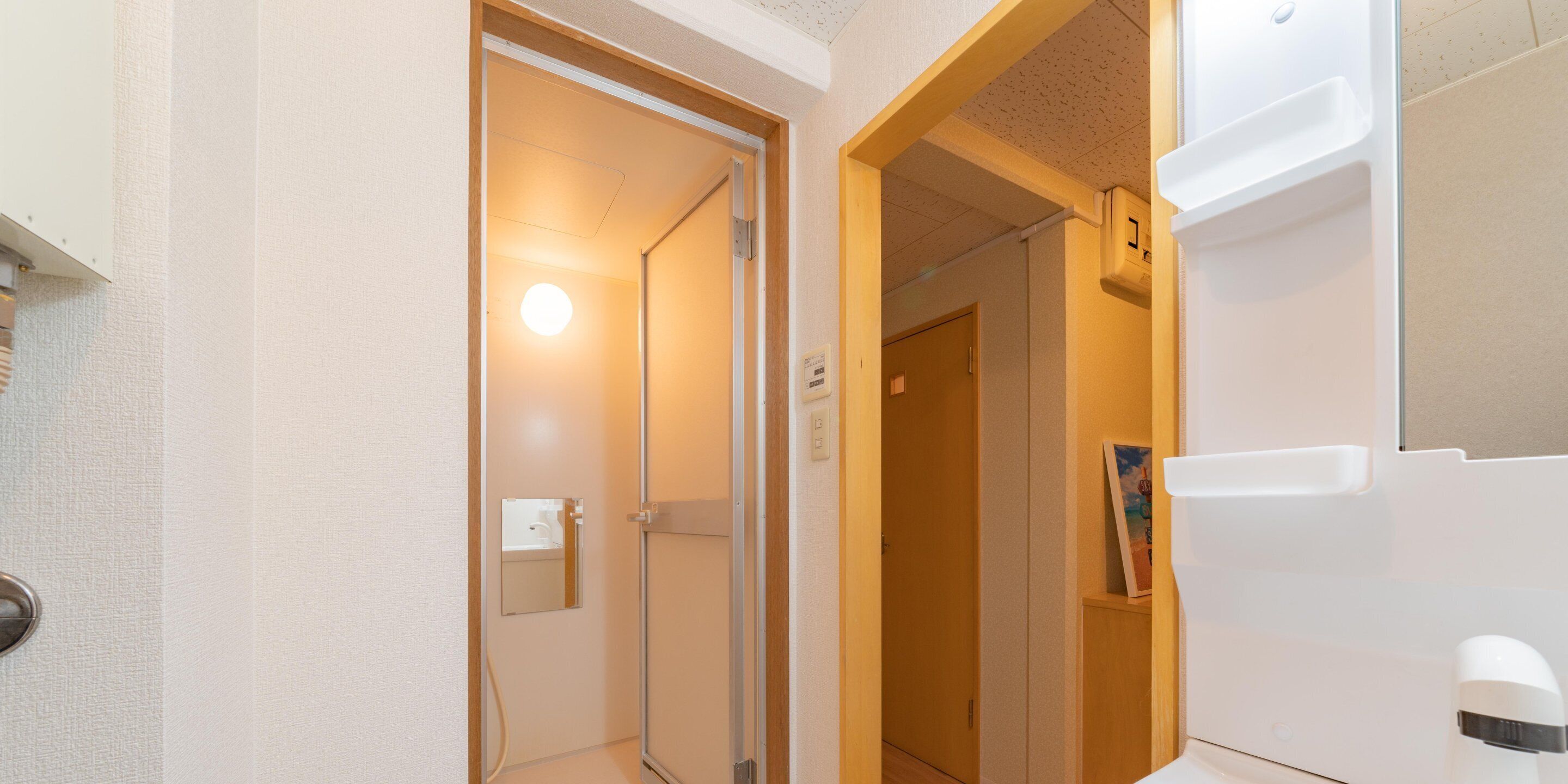 Habitación de hotel con ducha, espejo, puerta y un electrodoméstico blanco a la derecha.