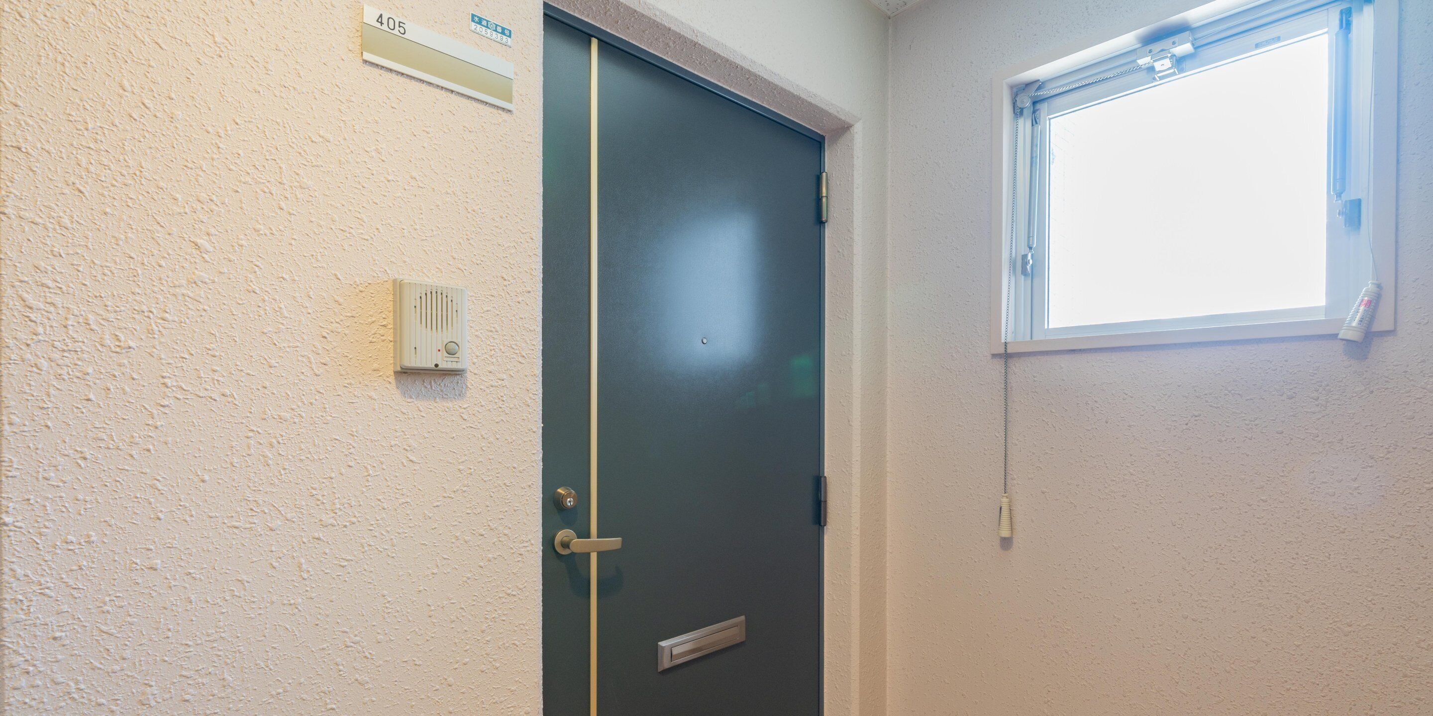 A door with a number plate, a window, and a wall-mounted intercom.