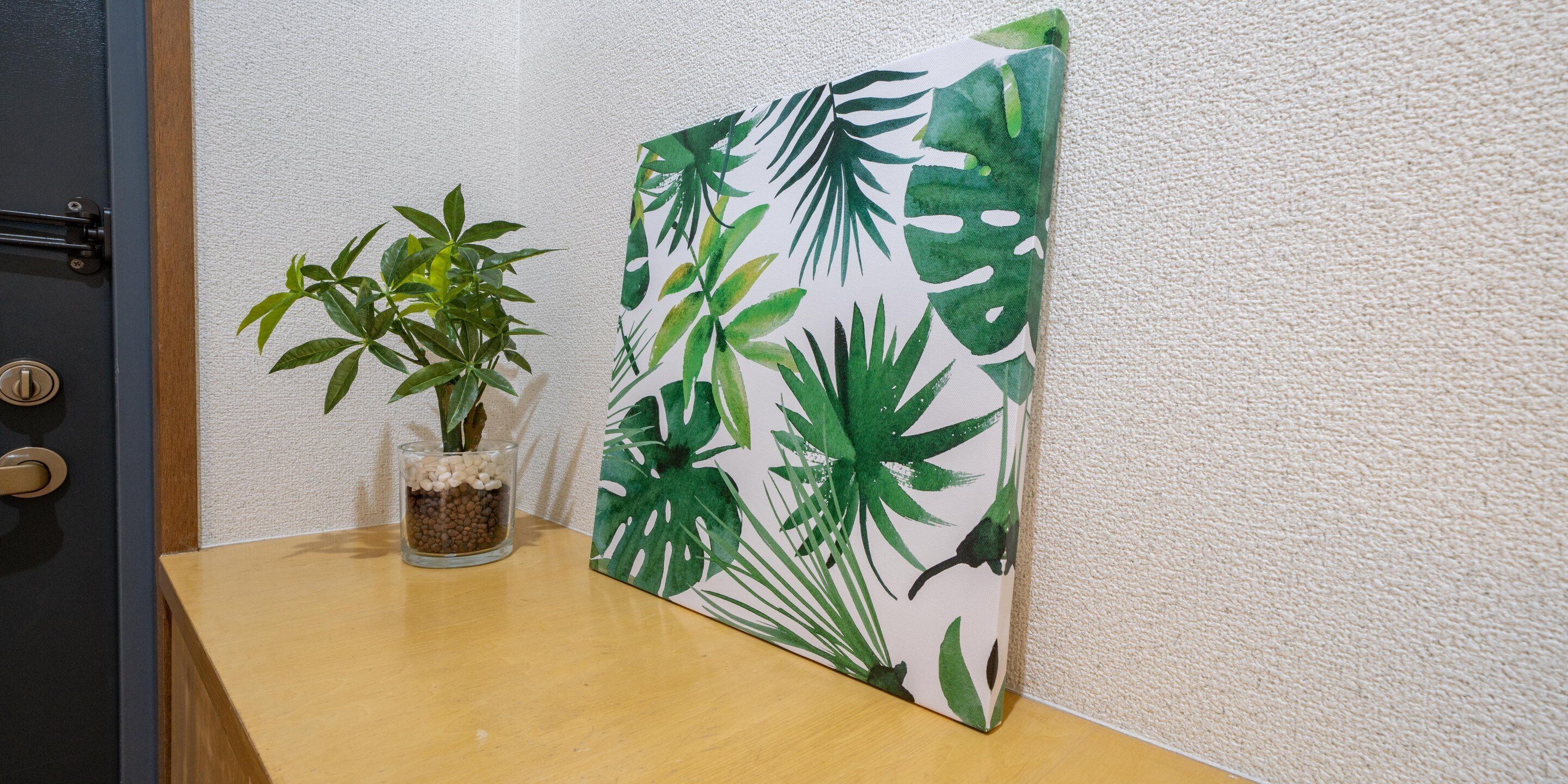 A wooden table with a potted plant and a framed artwork.