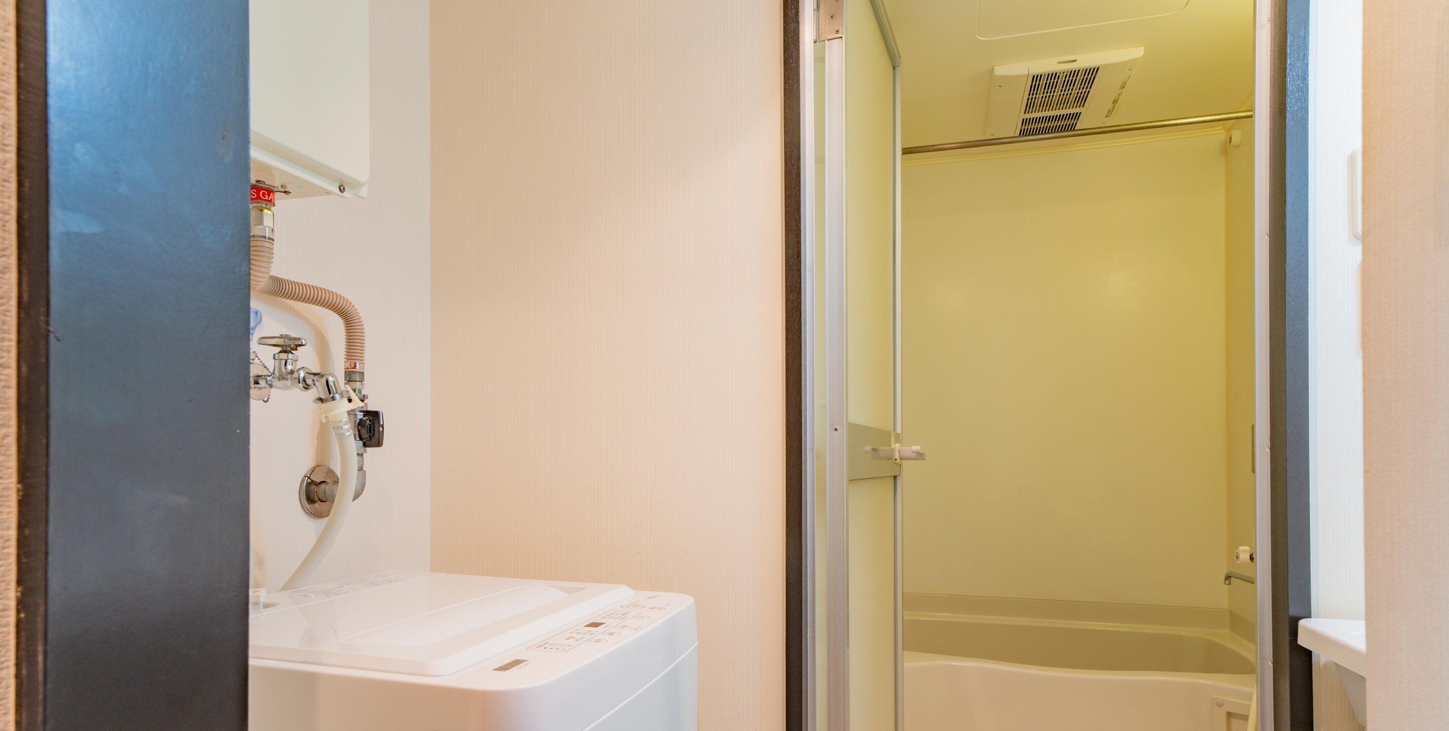 Une salle de bain équipée d’un lave-linge, d’une douche et de toilettes.