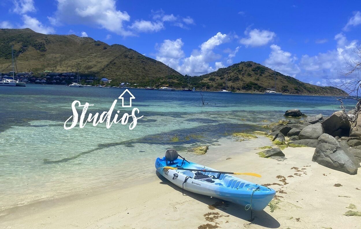A kayak on a beach with clear water and mountains in the background.