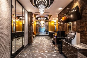 A modern hotel lobby with a marble floor, a reception desk, a TV, and a chandelier. - APA Hotel Hakataeki Chikushiguchi (Fukuoka)