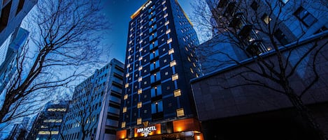 A tall hotel with a modern design, featuring a prominent 'APA HOTEL' sign at the entrance.