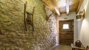 A stone-walled corridor with wooden beams, a wooden door, and a small table with a basket.