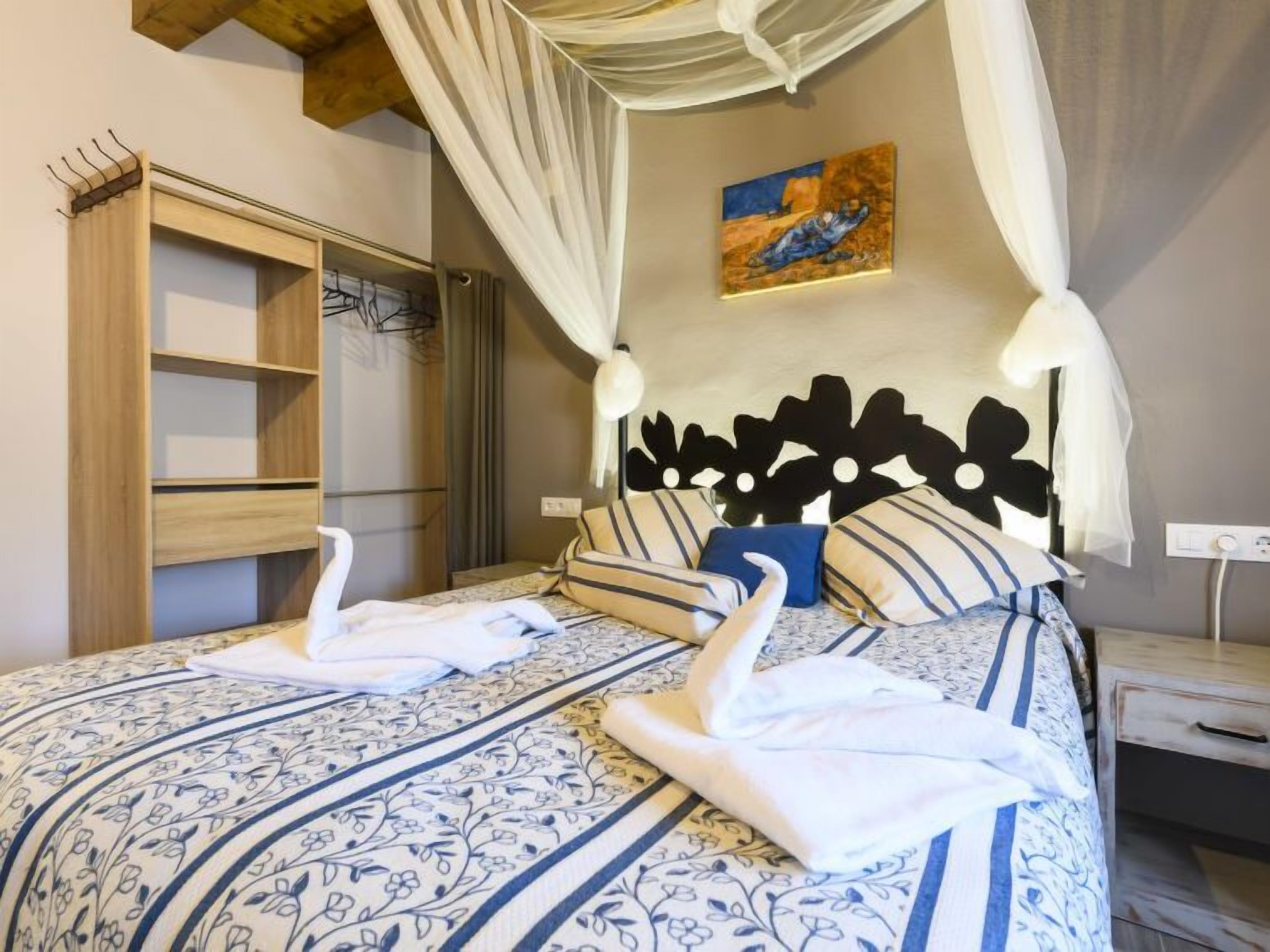 Une chambre à coucher avec un lit à baldaquin, une literie à rayures, une armoire en bois et un tableau accroché au mur.