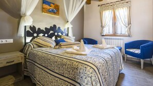 A bedroom with a bed, a nightstand, a chair, a window with curtains, and a painting on the wall.