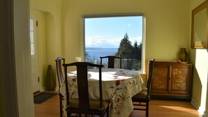 Ein Essbereich mit Tisch und Stühlen, Meerblick und einer Vitrine mit Dekoration.