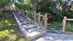 Eine Betonstufenanlage mit Holzgeländer, die zu einem befriedeten Bereich führt.