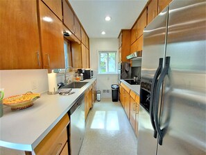 Kitchen features a sink, coffee maker, and trash can, with a window above the sink.
