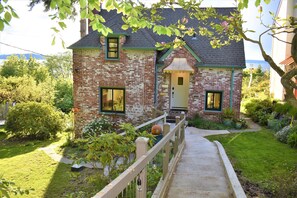 A brick house with a front porch, a small garden, and a pathway leading to the entrance. - Amazing and serene view house, art deco charmer, fully restored (Seattle)
