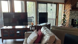 Un salon avec un canapé, un téléviseur, un meuble et une grande fenêtre.