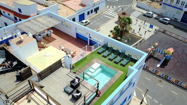 En tagterrasse med swimmingpool, liggestole og solsenge.