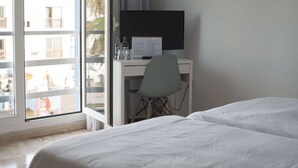 Et hotelværelse med en seng, et skrivebord med computer, en stol og udsigt ud.