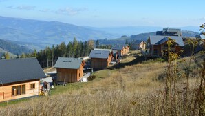 Un grupo de cabañas de madera con techos inclinados, enmarcado por colinas ondulantes y montañas lejanas.