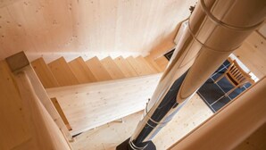 Una escalera de madera con barandilla que conduce a una habitación con suelo de baldosas y una silla.