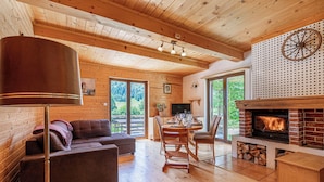 A cozy cabin interior with a fireplace, wooden furniture, and a dining area. - Kraševec Lodge with Garden & Pool, Bloke, Slovenia (Bloke)