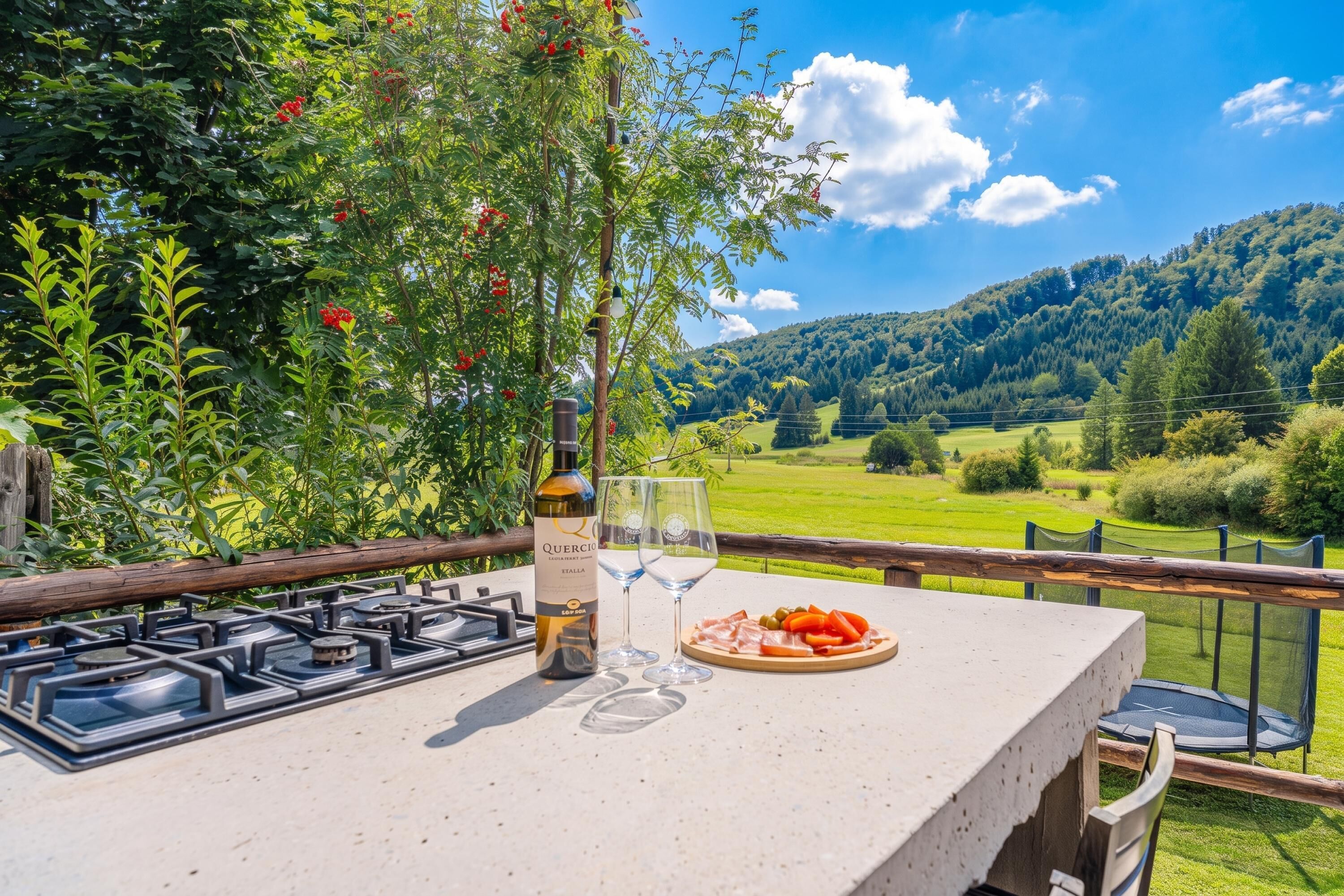 An outdoor dining area with a table, a bottle of wine, a glass, and a plate of food.