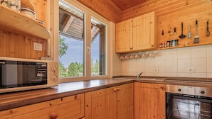 A wooden kitchen with a microwave, oven, and wooden cabinets. - Kraševec Lodge with Garden & Pool, Bloke, Slovenia (Bloke)