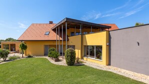 A modern two-story house with a yellow facade, a sloped roof, and a covered outdoor area. - Villa Prleški Raj - Pool, Sauna, Jacuzzi, Križevci pri Ljutomeru, Slovenia (Križevci pri Ljutomeru)