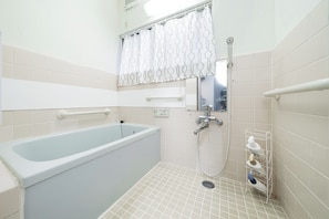 Un baño con bañera, ducha y barandilla.